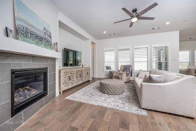 living room with hardwood / wood-style flooring, ceiling fan, and a fireplace