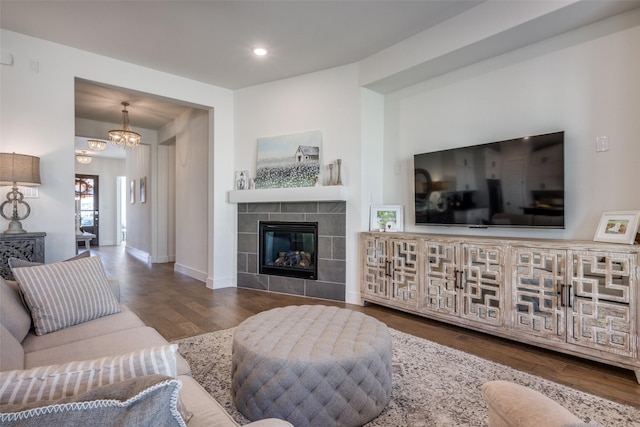 living room with dark hardwood / wood-style flooring, a notable chandelier, and a fireplace