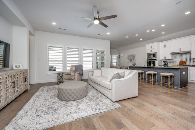 living room with ceiling fan, sink, and light wood-type flooring