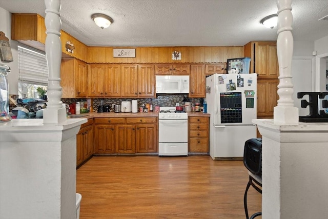 kitchen with tasteful backsplash, kitchen peninsula, light hardwood / wood-style flooring, and white appliances