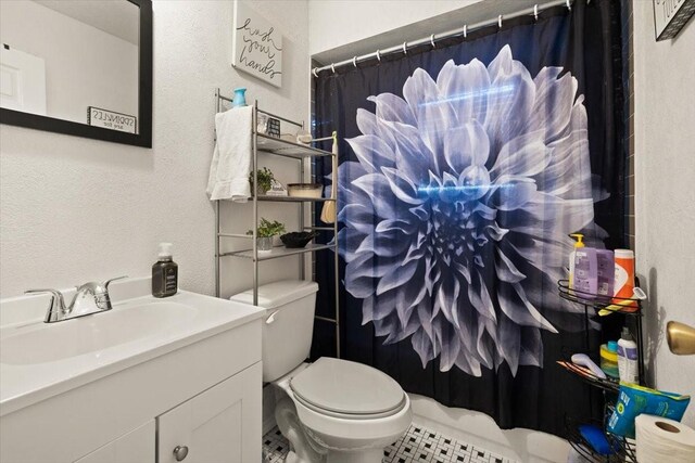 bathroom with tile patterned flooring, vanity, toilet, and walk in shower