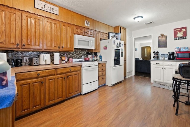 kitchen featuring tasteful backsplash, light hardwood / wood-style flooring, a textured ceiling, and white appliances