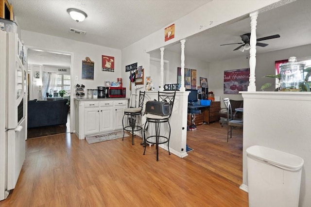 kitchen featuring ceiling fan, white fridge, light hardwood / wood-style floors, a textured ceiling, and white cabinets