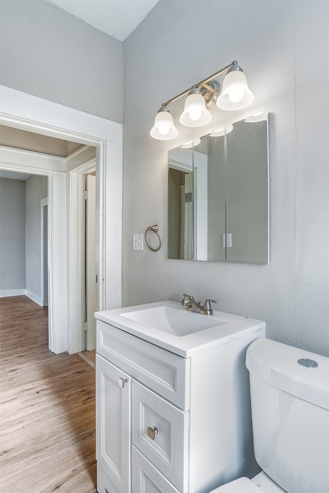 bathroom with hardwood / wood-style floors, vanity, and toilet