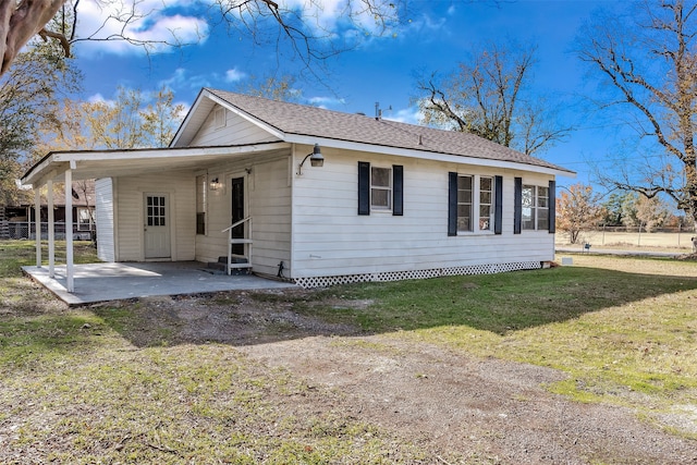 rear view of house featuring a carport and a lawn