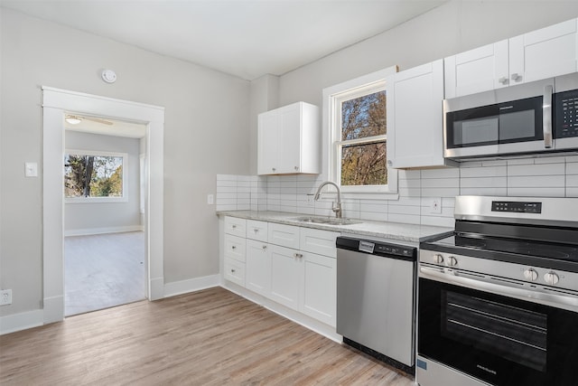 kitchen with white cabinets, light hardwood / wood-style floors, and stainless steel appliances