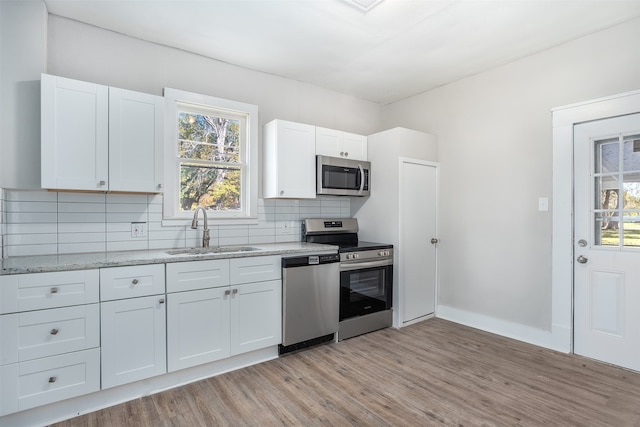 kitchen with appliances with stainless steel finishes, white cabinetry, plenty of natural light, and sink