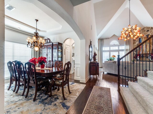 dining space with dark hardwood / wood-style flooring, a raised ceiling, and a chandelier