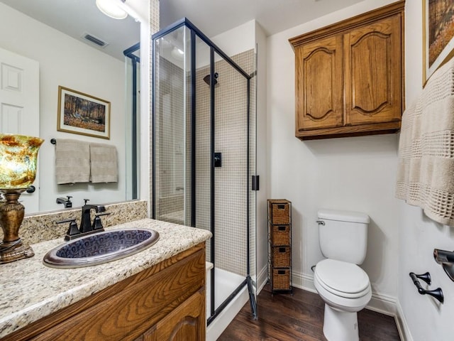 bathroom with an enclosed shower, vanity, toilet, and hardwood / wood-style flooring