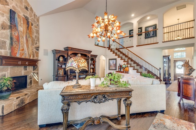 living room with dark hardwood / wood-style flooring, high vaulted ceiling, and a stone fireplace