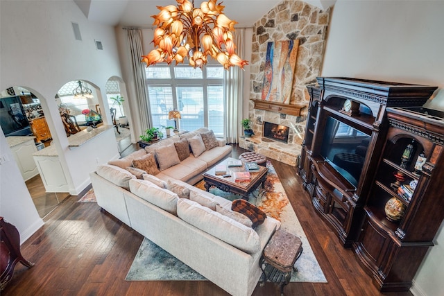 living room with dark wood-type flooring, a fireplace, a high ceiling, and an inviting chandelier