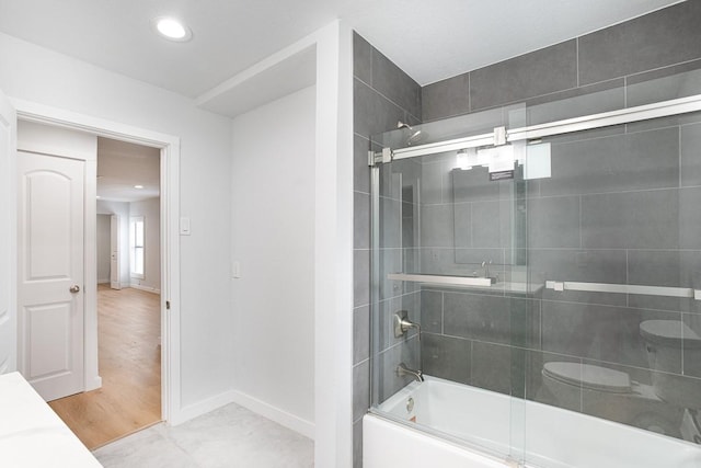 bathroom with hardwood / wood-style floors, toilet, and bath / shower combo with glass door