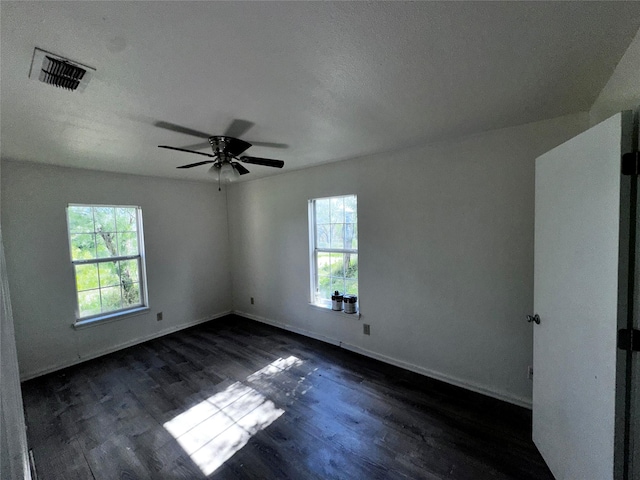 spare room featuring dark hardwood / wood-style floors, a healthy amount of sunlight, a textured ceiling, and ceiling fan