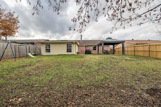 back of property featuring a gazebo, a yard, a playground, and a trampoline