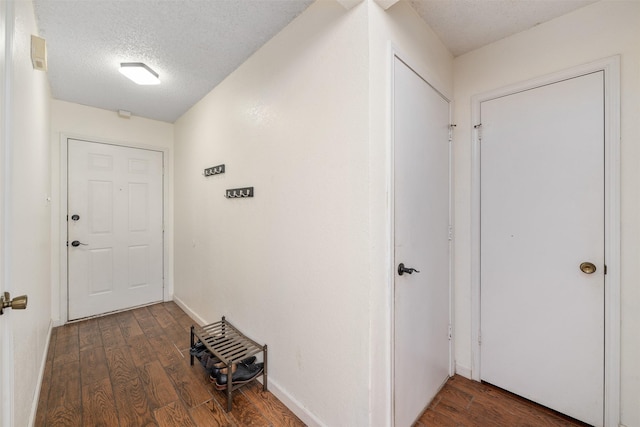 hall with a textured ceiling and dark hardwood / wood-style floors