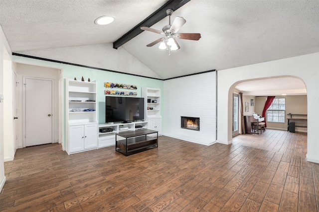 living room featuring lofted ceiling with beams, dark hardwood / wood-style floors, ceiling fan, a textured ceiling, and a fireplace