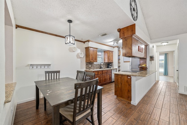 kitchen featuring kitchen peninsula, decorative backsplash, light stone countertops, a textured ceiling, and dark hardwood / wood-style floors