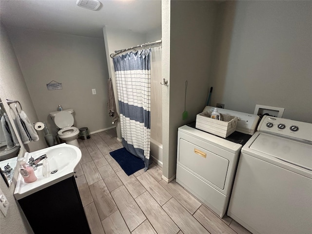 full bathroom with washer and clothes dryer, hardwood / wood-style floors, toilet, shower / bath combo with shower curtain, and vanity