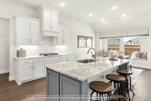 kitchen with dark hardwood / wood-style flooring, white cabinetry, a center island with sink, and sink