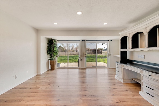 unfurnished office with light hardwood / wood-style floors and a textured ceiling