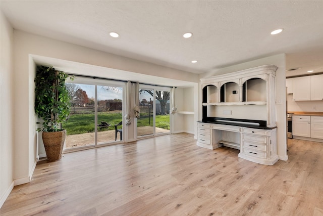 kitchen with white cabinets, a textured ceiling, and light hardwood / wood-style flooring