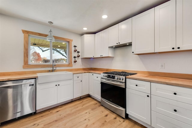 kitchen with wood counters, pendant lighting, stainless steel appliances, and sink