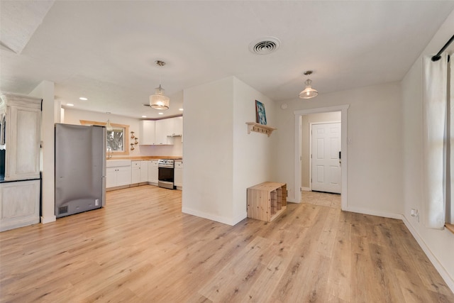 kitchen featuring pendant lighting, wood counters, light wood-type flooring, appliances with stainless steel finishes, and white cabinetry