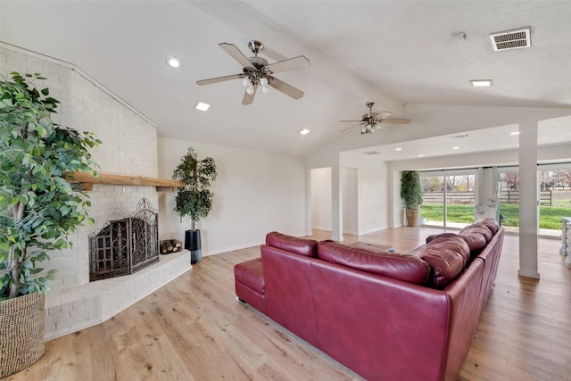 living room with ceiling fan, a fireplace, lofted ceiling with beams, and light wood-type flooring