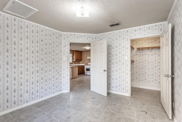 empty room featuring crown molding, light tile patterned floors, and a textured ceiling