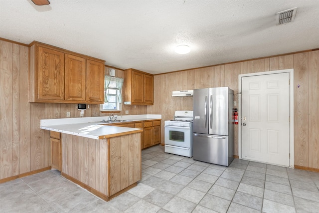 kitchen with exhaust hood, wooden walls, white gas stove, kitchen peninsula, and stainless steel refrigerator