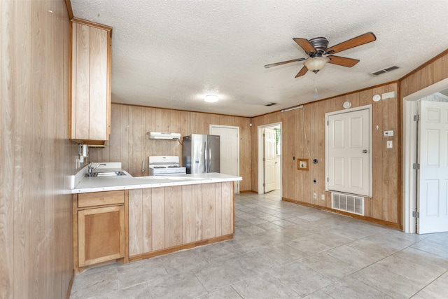 kitchen with ceiling fan, sink, kitchen peninsula, stainless steel fridge, and white range with gas cooktop