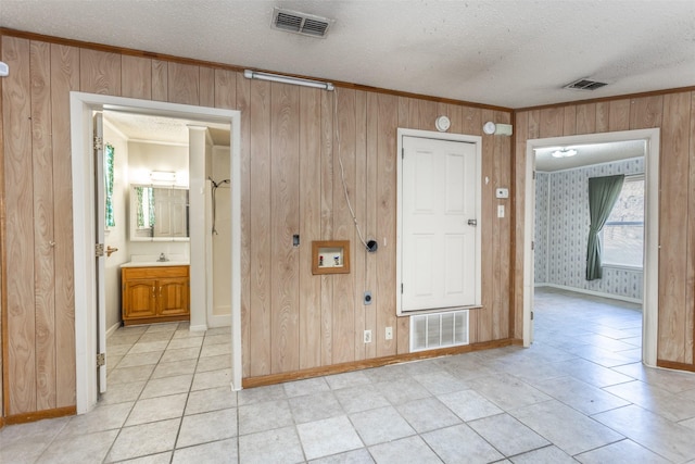 interior space featuring wood walls, light tile patterned flooring, and a textured ceiling