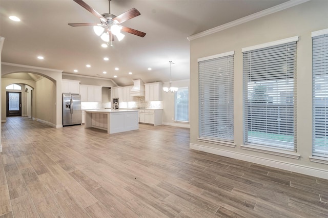 kitchen with pendant lighting, crown molding, a kitchen island with sink, and stainless steel refrigerator with ice dispenser