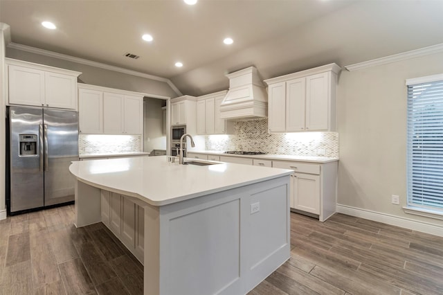 kitchen featuring appliances with stainless steel finishes, custom exhaust hood, sink, white cabinets, and an island with sink