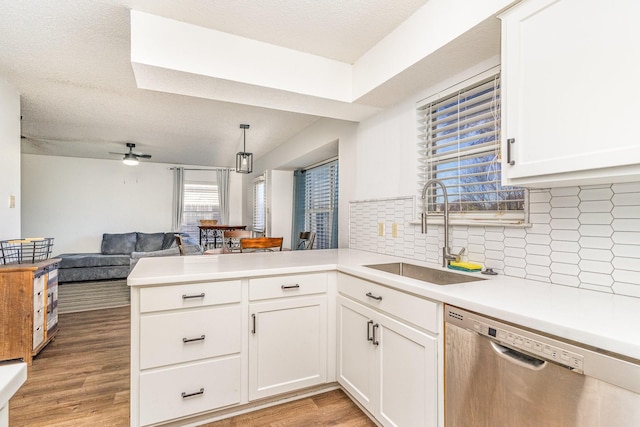 kitchen with stainless steel dishwasher, kitchen peninsula, sink, and tasteful backsplash