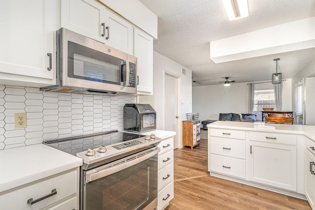 kitchen featuring decorative backsplash, appliances with stainless steel finishes, and white cabinets