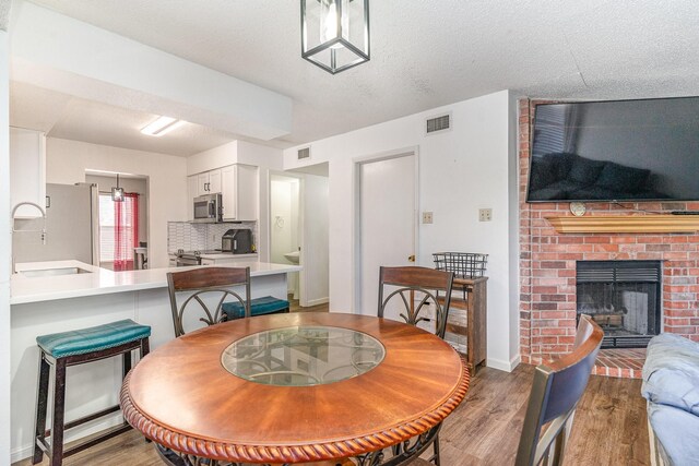 dining area featuring a fireplace, a textured ceiling, hardwood / wood-style flooring, and sink