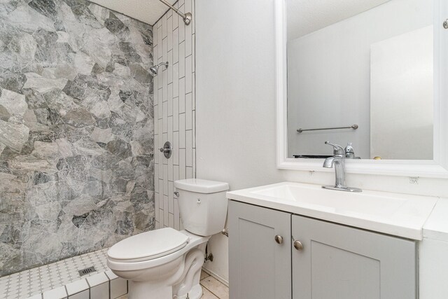 bathroom with vanity, a tile shower, a textured ceiling, and toilet