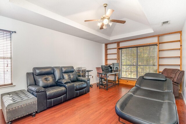 living room featuring a tray ceiling, a wealth of natural light, and hardwood / wood-style flooring