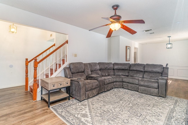 living room with wood-type flooring, a textured ceiling, and ceiling fan