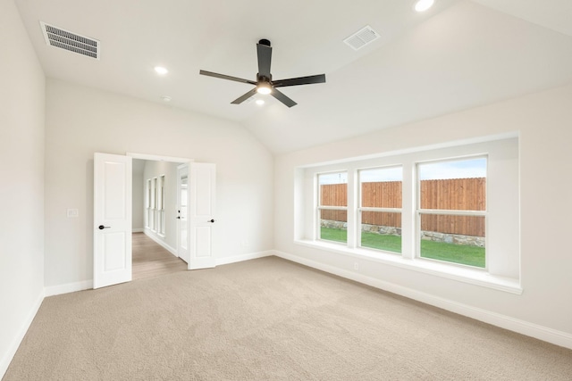 unfurnished room with a ceiling fan, visible vents, vaulted ceiling, baseboards, and carpet flooring