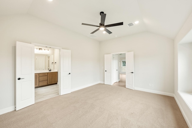 unfurnished bedroom featuring connected bathroom, light carpet, visible vents, baseboards, and vaulted ceiling