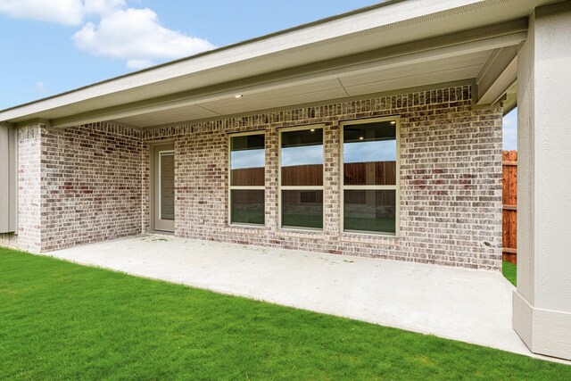 back of house featuring brick siding and a patio area