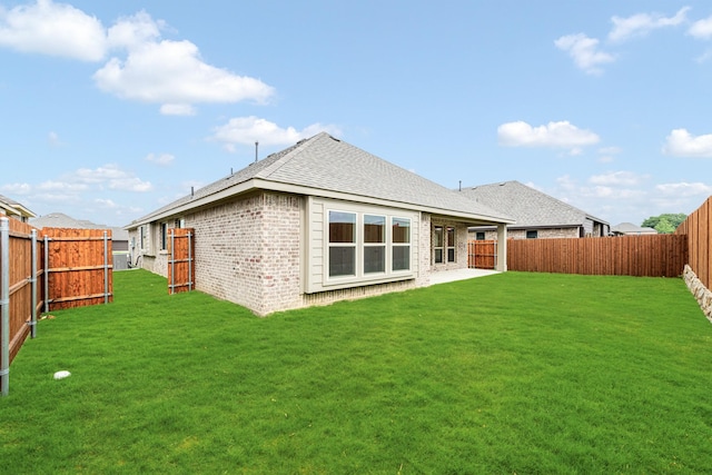 rear view of house with a lawn, brick siding, and a fenced backyard