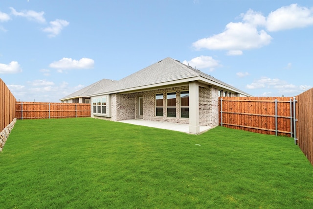 back of house with a yard, brick siding, a fenced backyard, and a patio area