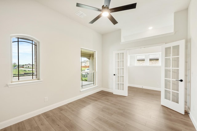unfurnished room with visible vents, wood finished floors, baseboards, french doors, and a ceiling fan