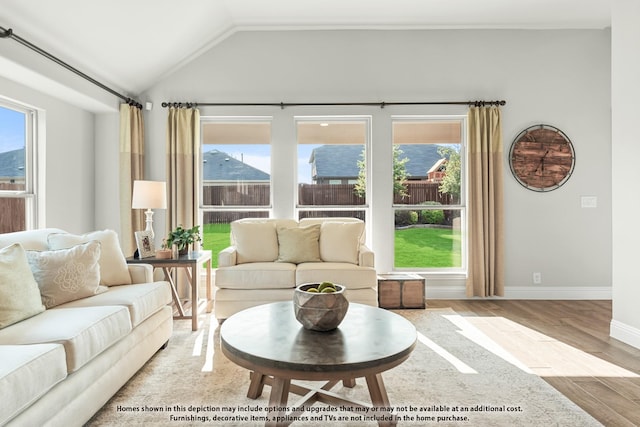 living room with a healthy amount of sunlight, vaulted ceiling, and light wood-type flooring