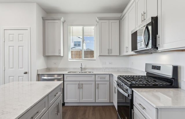 kitchen featuring light stone countertops, dark wood-type flooring, stainless steel appliances, sink, and gray cabinets