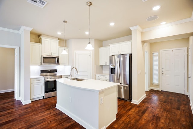 kitchen featuring appliances with stainless steel finishes, decorative light fixtures, white cabinetry, sink, and a center island with sink