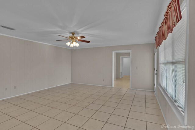 unfurnished living room with a fireplace, ceiling fan, ornamental molding, and light tile patterned flooring